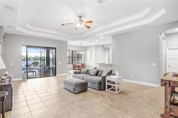 VIEW OF GREAT ROOM -SLIDING GLASS DOORS LEADING TO COVERED/SCREENED IN LANAI/POOL -- , KITCHEN, DINETTE, ENTRANCE : TRAY CEILINGS -- DOOR ON THE RIGHT LEADS TO INSIDE LAUNDRY /UTILITY ROOM
