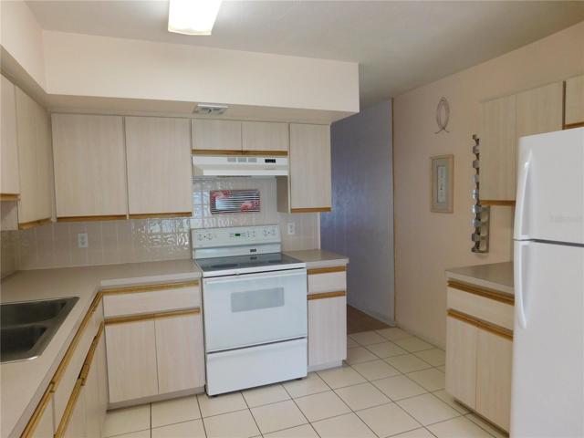View of Kitchen showing refrigerator, additional cabinets, and there is even a wine rack.