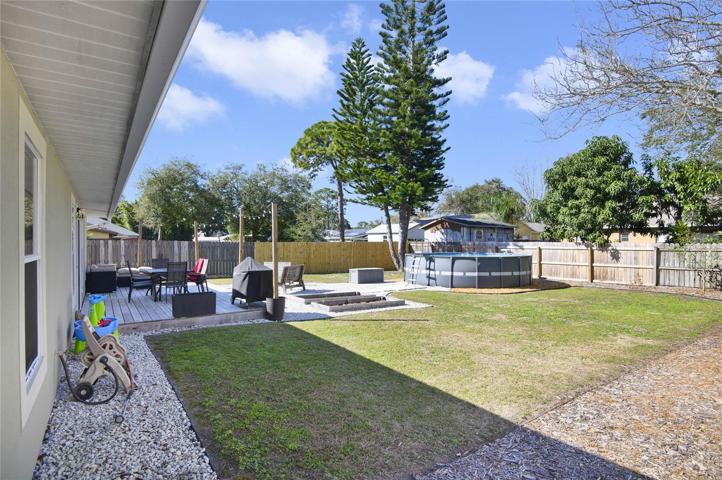 Fenced-in backyard with above ground pool and deck
