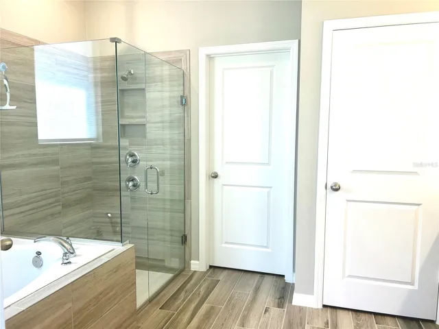 Luxury awaits in primary suite bathroom with soaking tub and rain shower