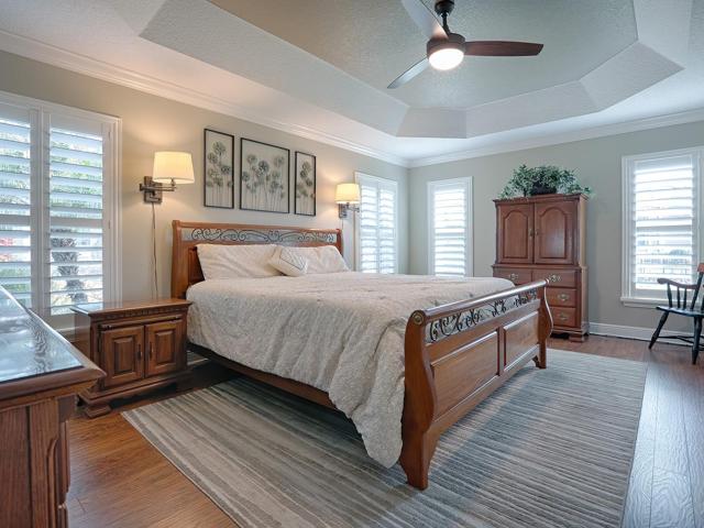 PRIMARY BEDROOM WITH LOTS OF WINDOWS AND NATURAL LIGHTING.  PAINTED TRAY CEILING WITH CUSTOM CEILING FAN.