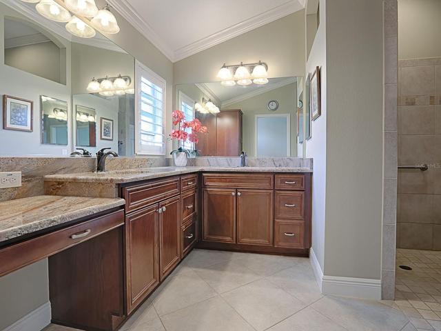PRIMARY BATH WITH GRANITE COUNTERS, A VANITY, DUAL SINKS, SEPARATE TOILET ROOM AND A ROMAN SHOWER.