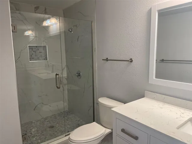 Newly tiled primary shower, new toilet, vanity, sink, countertop, faucets, flooring.