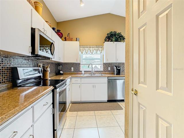 Kitchen has stainless steel appliances and tile back-splash.