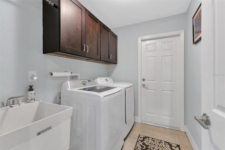 Inside laundry room with washer, dryer, sink and extra cabinets.