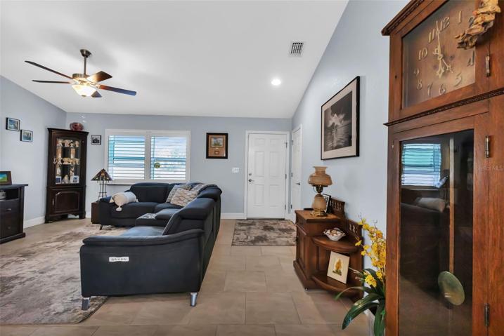 Living room features vaulted ceilings, plantation shutters and porcelain tile throughout