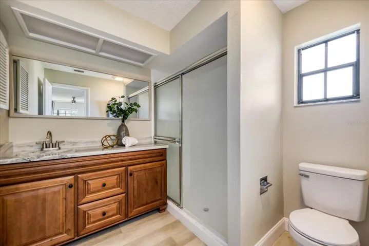 New wood vanity with solid surface counter & new mirror. Step in shower & waterproof luxury vinyl plank flooring is not as slippery as tile