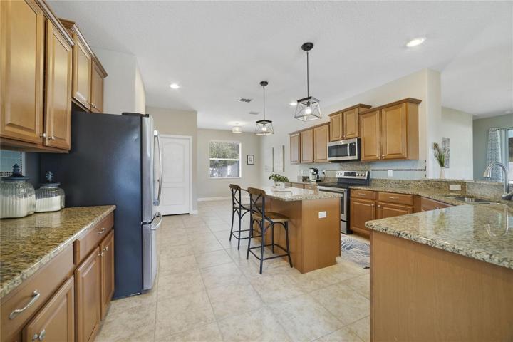 The dining area flows right into the home chef's dream kitchen featuring seemingly endless cabinetry with pull out storage in the bottom and for your trash, GRANITE COUNTERS, a closet pantry, STAINLESS STEEL APPLIANCES, a center ISLAND with bar seating perfect for entertaining friends and a dinette for casual meals with family!