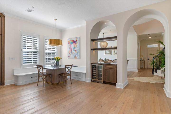 informal dining area with built-in nook, breakfast bar and wine refrigerator looking to front of home with front foyer, as well.   Office to left near foyer, but not in view.