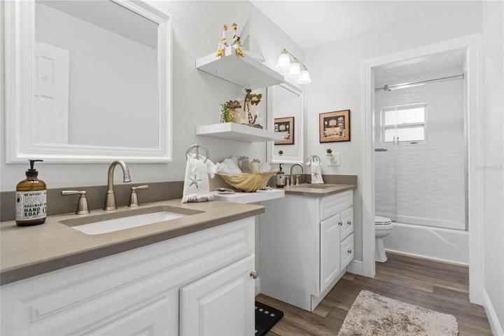 Guest Bathroom with Dual Vanities & Tub with Glass Doors