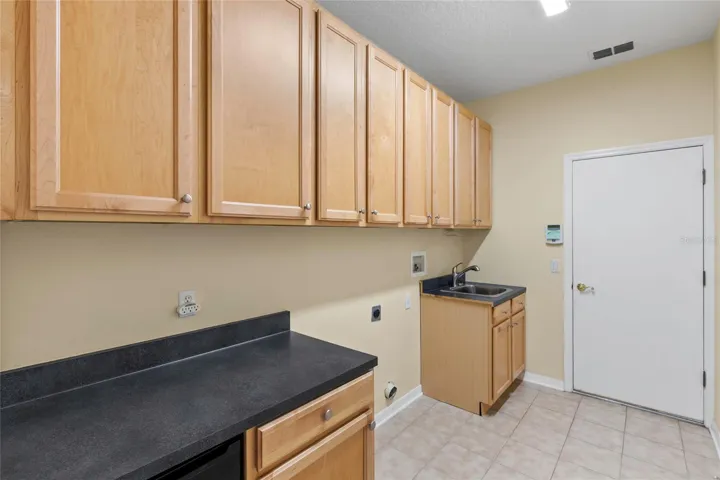 Spacious Laundry room with extra cabinetry plus counter space for work area plus stainless-steel sink