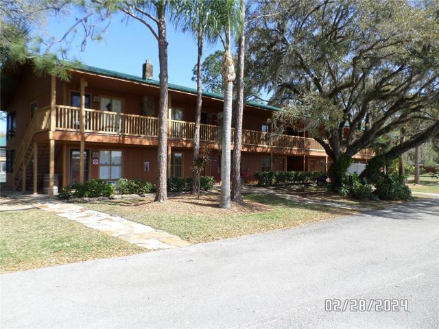 View of building with oak and palm trees providing shade.