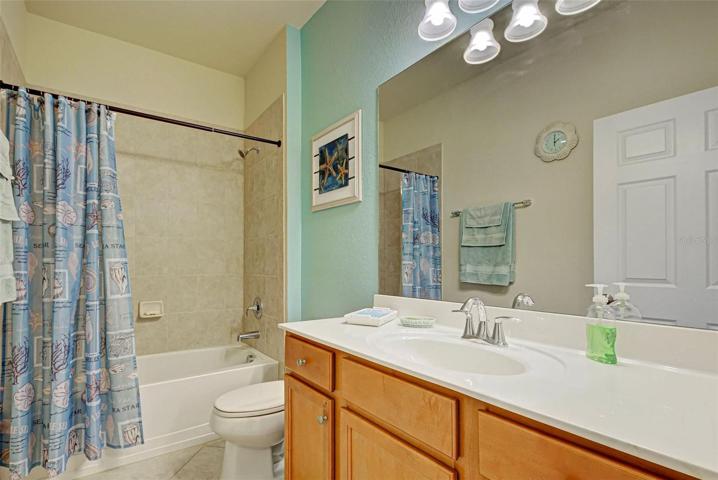 The guest bathroom has a tub and shower combination.