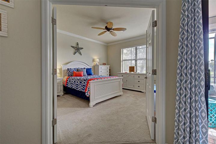 Double doors lead the way to the spacious primary bedroom is crown molding and a ceiling fan.