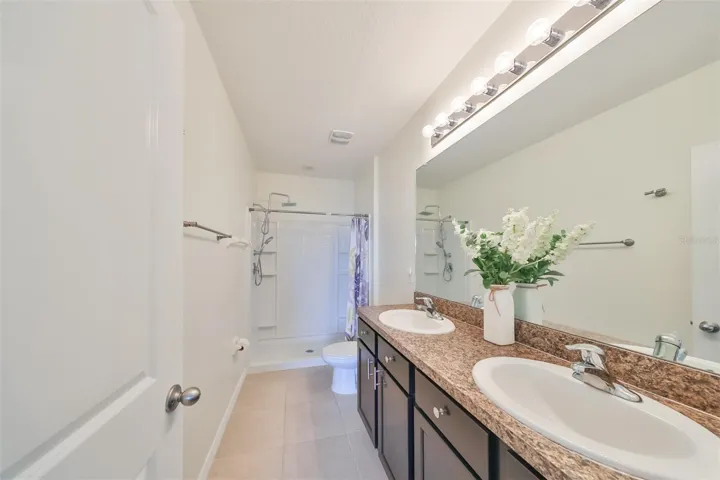Primary en-suite sanitized bathroom boasts of dual sinks, walk-in shower, high-end Shower faucets and bright lights.