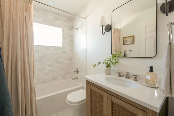 The primary bathroom exudes classic charm with marble floors and marble shower walls, polished nickel fixtures, a wood vanity with Statuario quartz top, and wall sconces.
