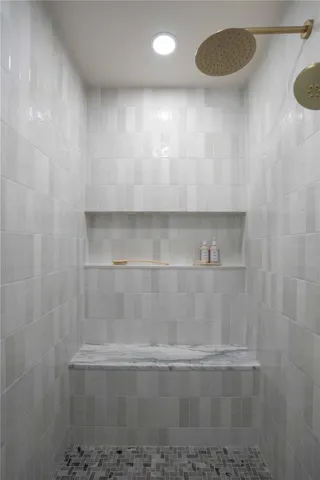 Luxurious spa shower includes marble floors, a niche stretching from wall to wall, a bench, glass door with polished nickel hardware.