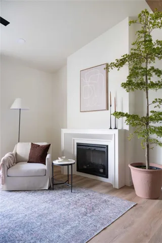 The fireplace is surrounded by a custom-made beveled mantel and is situated against a bumped out wall with a recessed outlet for a TV.