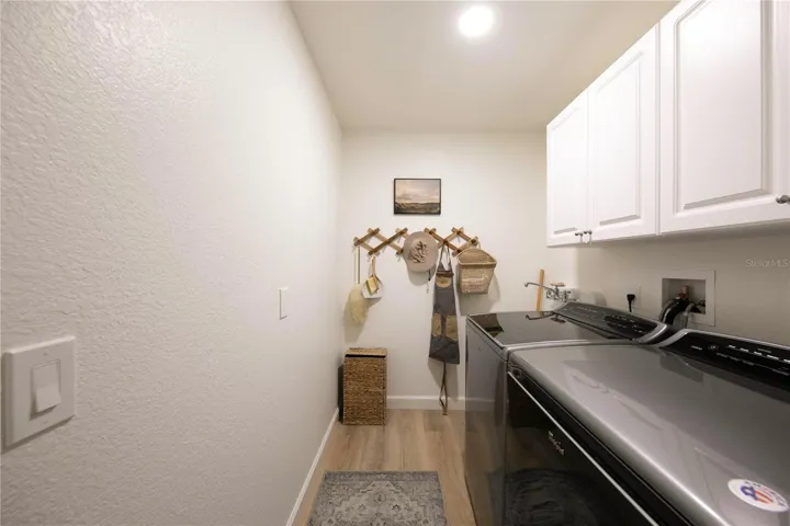 Laundry room equipped with high-quality Samsung appliances, sink and upper cabinets.