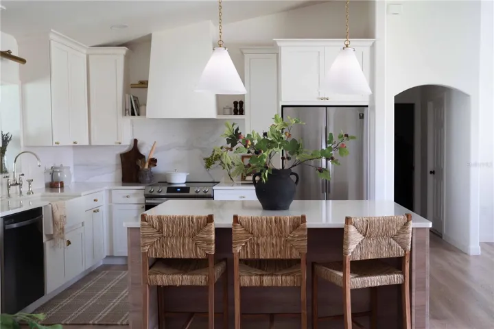 Other features include a farmhouse sink, Samsung appliances with a water connection for the refrigerator, sliding trash bins, a pantry with sliding drawers and a hidden outlet for the microwave, LED recessed lights, articulating sconces, and island lights.