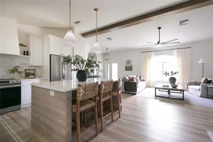 To add depth and character, a mix of warm white cabinetry and a faux wood island is used, complemented by a combination of aged brass and polished nickel finishes.