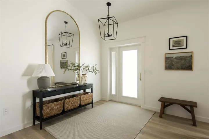 Crown molding around the entry door, tall ceiling and beautiful light fixture.