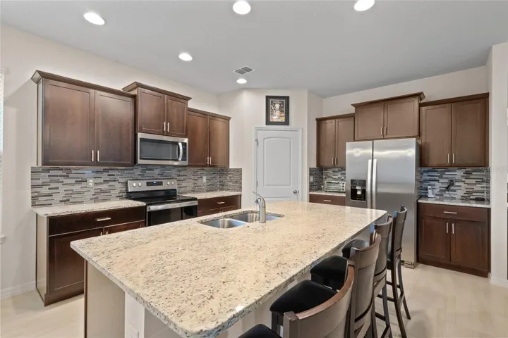 Kitchen with espresso cabinets, granite counters, large breakfast bar, newer backsplash. Stainless appliances are all included!