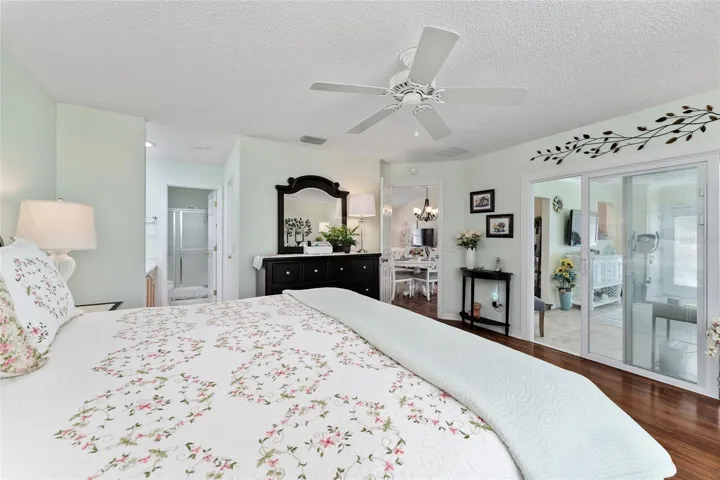 PRIMARY BEDROOM - ENSUITE BATHROOM (L), Doorway between PRIMARY BR & DINING ROOM (back center), and SLIDING GLASS DOORS w/ BUILT-IN BLINDS allow access to FLORIDA ROOM (R)