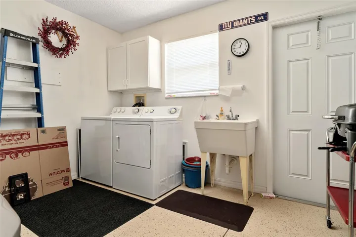 WASHER, DRYER, & LAUNDRY SINK in garage. Exit door (R) leads to open patio.