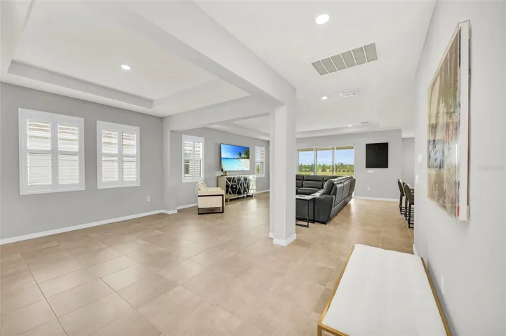 Formal dining room seamlessly connects to the living area, bathed in ample natural light. Custom shutters adorn every window for a touch of sophistication.