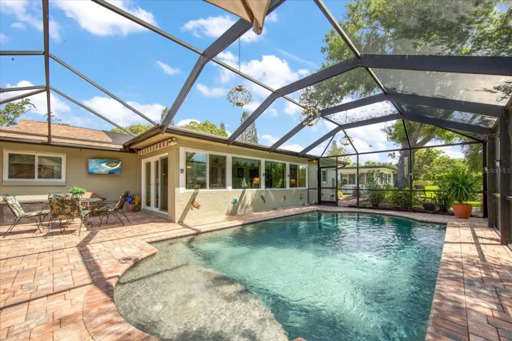 An easy step down pool entry with a bubbler fountain on the top seating platform. Outdoor wall TV conveys with house~