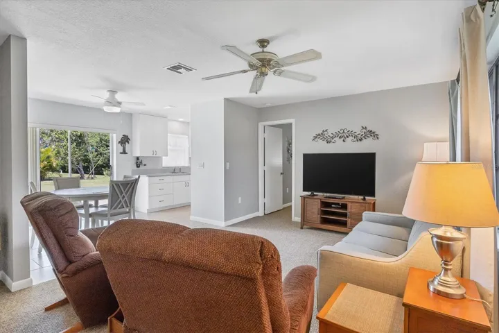 open view from entry, living room, dinette area and partial kitchen, door at rear of photo is primary suite side