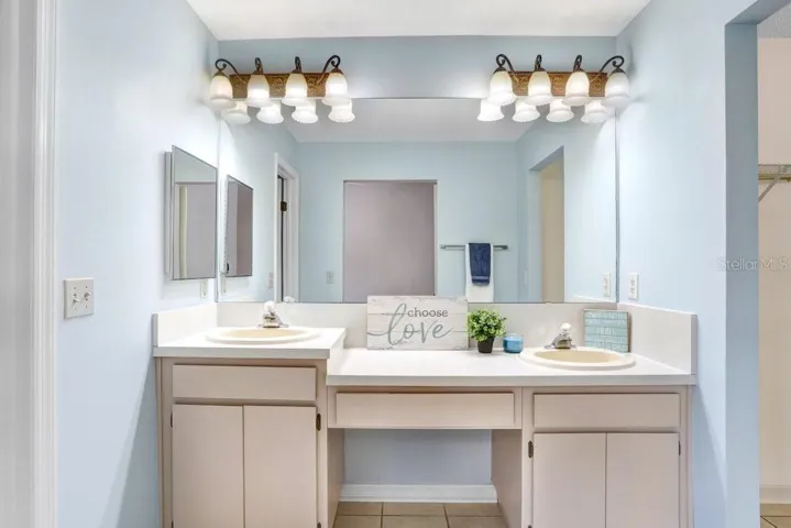 The master ensuite features a walk-in closet, dual sinks, lots of storage cabinets, a linen closet, ceramic tile flooring, a door to the toilet/shower area, and a garden tub/shower combo.