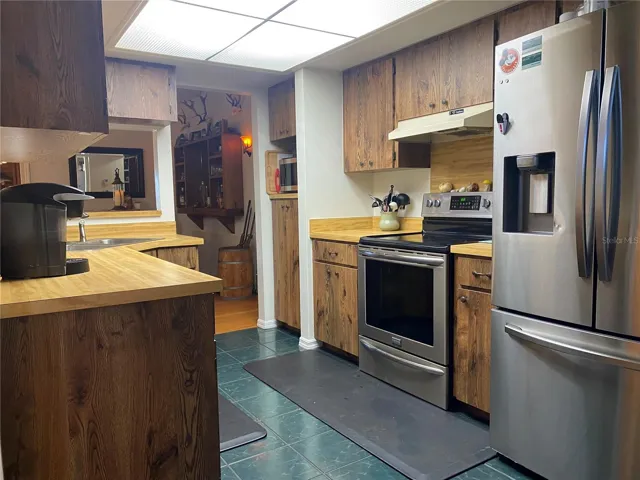 Kitchen has tile floors and stainless steel appliances.
