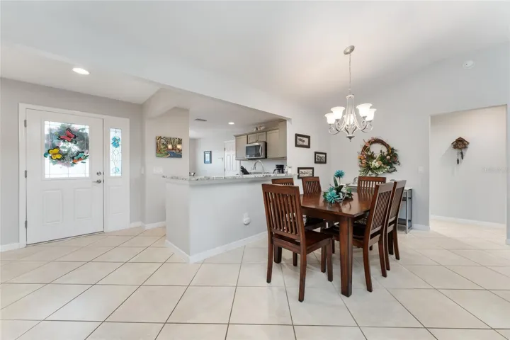 FOYER (L), DINING AREA (front center) & KITCHEN (back center). Hallway (far R) leads to INDOOR LAUNDRY (to L) & PRIMARY SUITE (to R). Note the DIAGONAL SET TILE FLOORS.