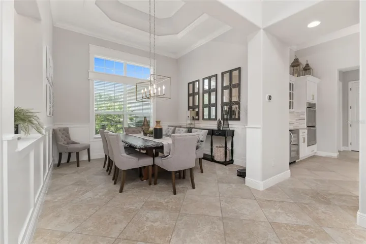 View of formal DINING ROOM shows octagonal TRAY CEILING w/ CROWN MOLDING, custom WOOD WALL PANELING under chair rail