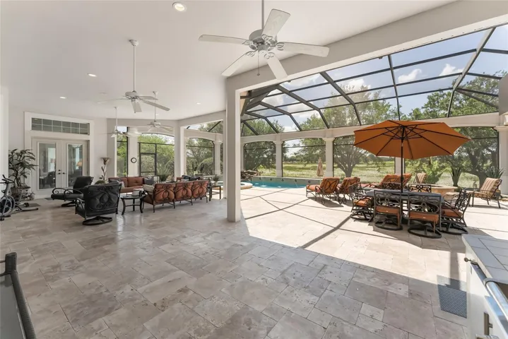 TRAVERTINE TILE graces all areas in OPEN LANAI & MANSARD SCREENED POOL ENCLOSURE.