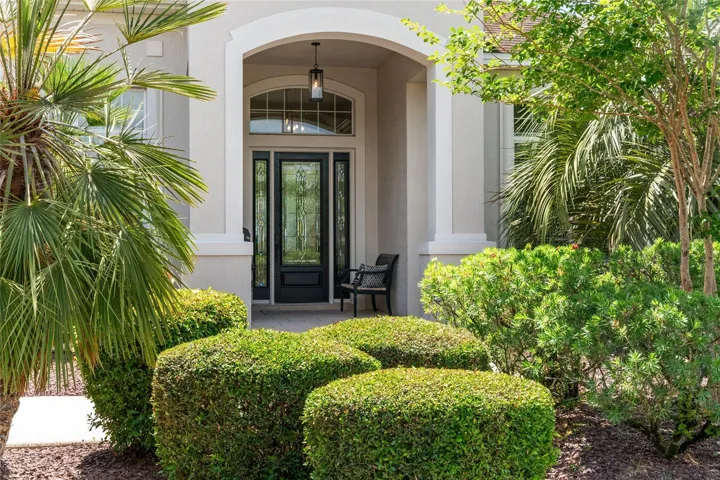 COVERED FRONT PORCH surrounded by MATURE LANDSCAPING w/ updated ROCK FILLED landscaped beds w/ STACKED STONE HARDSCAPING & CONCRETE CURBING.