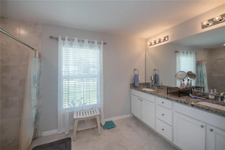 Primary ensuite bathroom with step-in shower and double sink vanity.