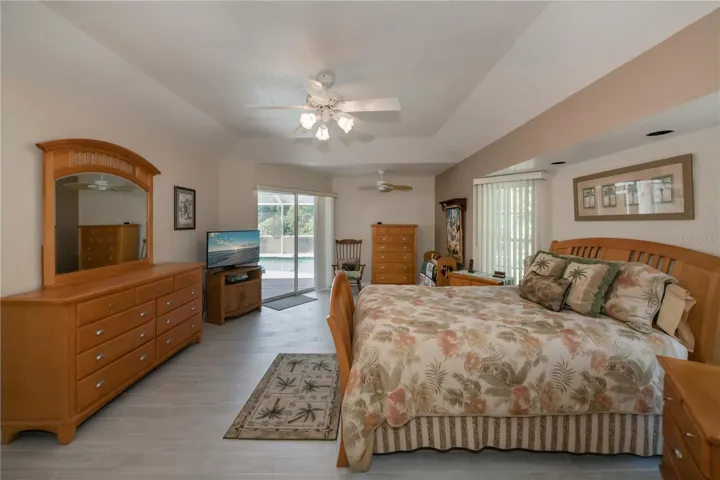 Tray ceiling primary ensuite bedroom opens to the pool & lanai.