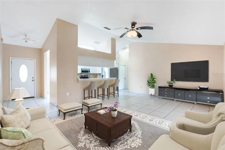 The foyer opens up to a spacious EAT-IN KITCHEN and the living room beyond where HIGH CEILINGS add to the bright open feel and sliding glass doors give you access to a large FLORIDA ROOM for additional flexible space. Virtually Staged.