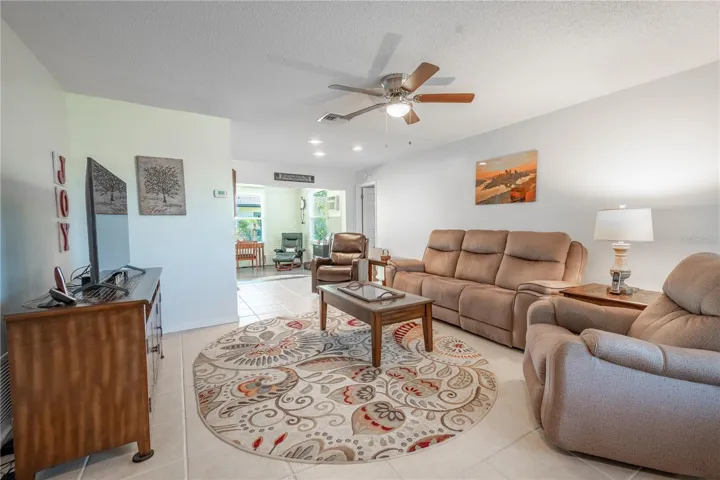 The living room features, ceramic tile flooring, a neutral color palette and a ceiling fan for year round comfort.