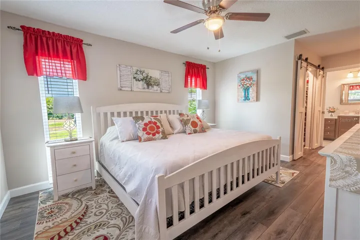 The primary bedroom features vinyl plank flooring, a ceiling fan, walk-in closet and an ensuite bathroom.