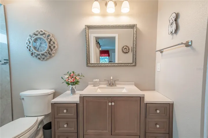 The primary ensuite bathroom features a stunning multi-level vanity with framed mirror and downlight fixture.