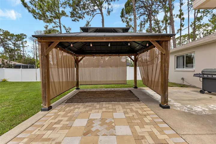 Concrete and pavered lanai with pergola.