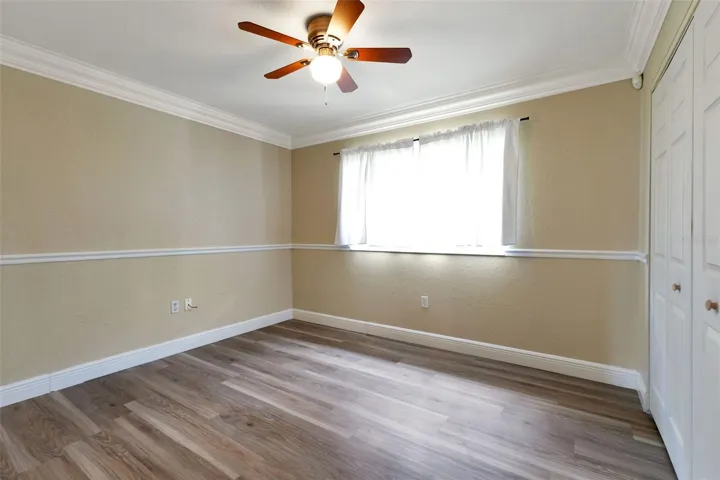 Guest bedroom with laminate flooring and built in closet.