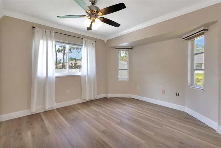 Master bedroom with laminate flooring, crown molding and plenty of windows for natural light.