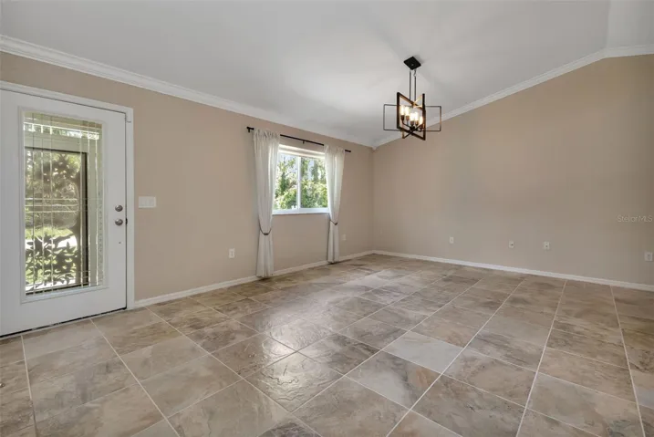 Open concept with vaulted ceilings and crown molding. View of living room with tile flooring.