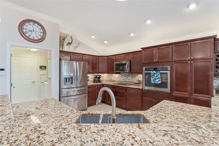 GRANITE COUNTERTOPS, TILE BACKSPLASH, AMBIENT AND HIGH HAT LIGHTING THROUGHOUT KITCHEN.