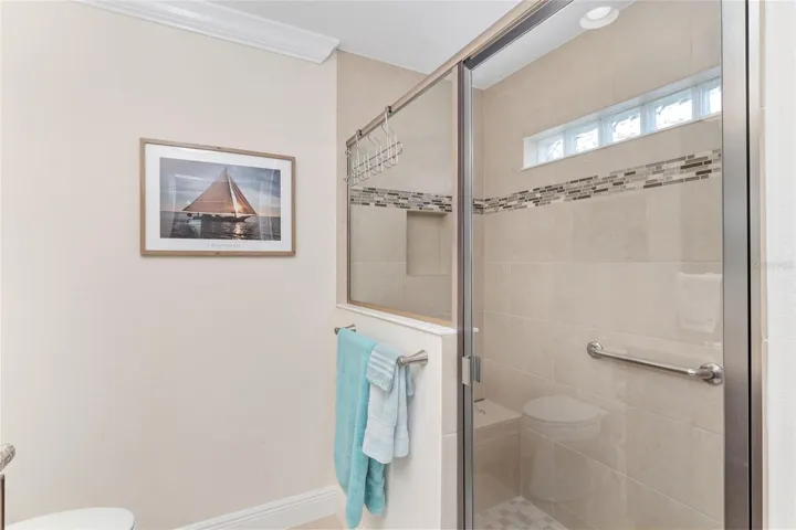 FRONT GUEST ROOM SHOWER WITH INLAY TILE DETAIL, BENCH AND GLASS ENCLOSURE.